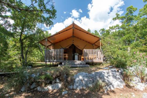 una cabaña en el bosque con un techo grande en Lodge du Berlandou, en Escragnolles