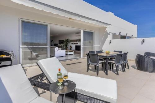 un patio con sillas blancas y una mesa con copas de vino en Modern 3 Bedrooms Penthouse With A Breathtaking Valletta View, en Sliema
