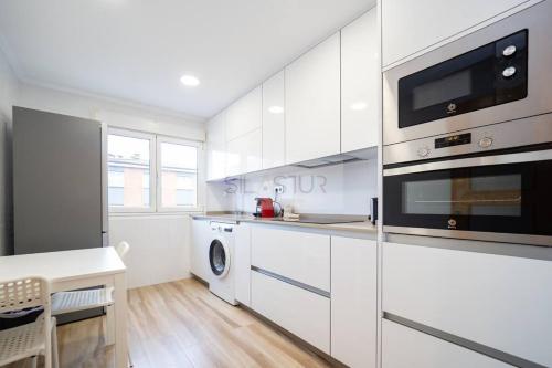uma cozinha branca com máquina de lavar e secar roupa em Montes Suites em Gijón