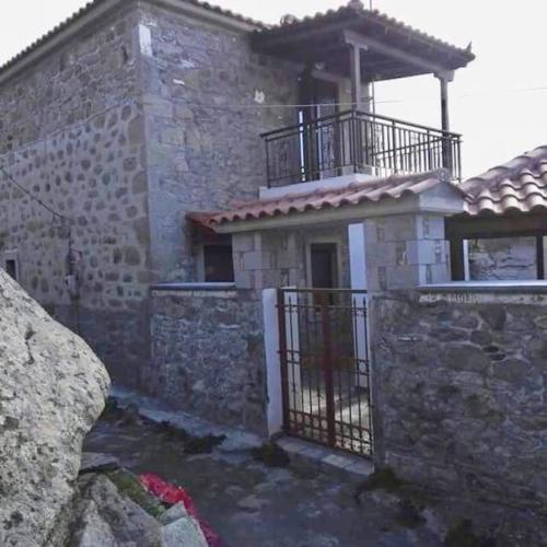 a stone house with a balcony on top of it at Traditional stone-built house with great view in Kondiás