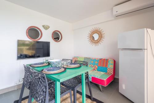 a dining room with a green table and chairs at L'Isula - Appt pour 5 climatisé avec piscine in LʼÎle-Rousse