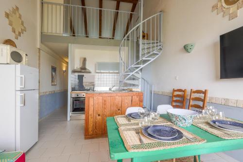 een eetkamer met een groene tafel en een keuken bij Le Rocher - Appt pour 6 climatisé avec piscine in LʼÎle-Rousse