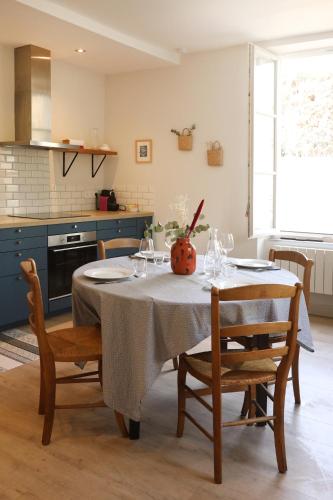 une cuisine avec une table et deux chaises et une cuisine avec des armoires bleues dans l'établissement La Maison du Clocher by La Boîte En Plus, à Courteuil