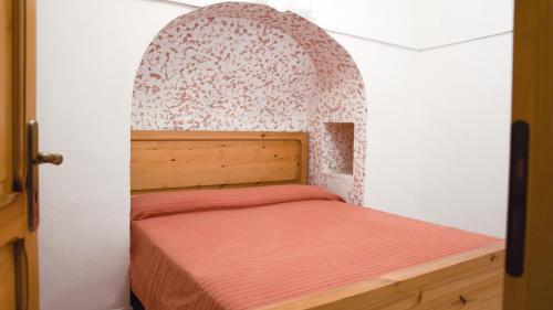 Una cama pequeña en una habitación con un arco encima. en Sea View, Nature & Barbecue - Authentic "Dammusi", en Pantelleria