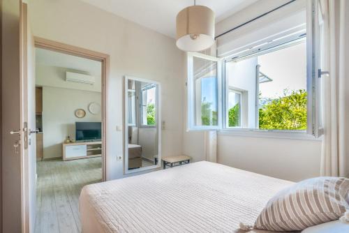 a white bedroom with a bed and a large window at The Holiday House 1 in Kavrokhórion