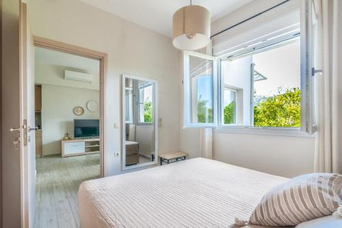 biała sypialnia z łóżkiem i dużym oknem w obiekcie The Holiday House 1 w mieście Kavrokhórion