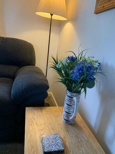 a vase with blue flowers sitting on a table at Cosy cottage between Penzance and St Ives in Gulval