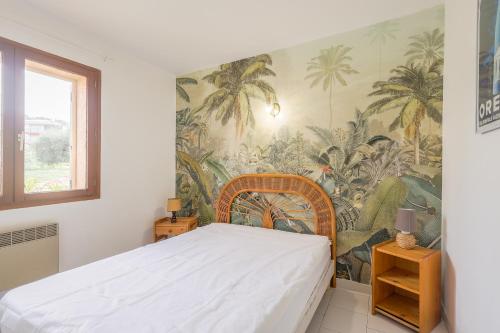 une chambre avec un lit avec un papier peint tropical dans l'établissement La Petra Marinella - Appt climatisé avec piscine, à LʼÎle-Rousse