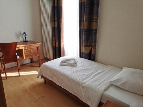 Schlafzimmer mit einem Bett, einem Schreibtisch und einem Fenster in der Unterkunft Beaumane Rooms in Caux sur Montreux