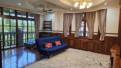 a living room with a blue chair and windows at CASA ALRAWDAH in Kampung Padang Masirat