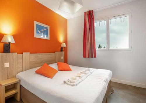 ein Schlafzimmer mit einem Bett mit orangefarbenen Wänden und einem Fenster in der Unterkunft Cosy Gaïa - Appt climatisé avec piscine partagée in Sète