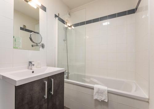 a white bathroom with a tub and a sink and a bath tub at Cosy plage - Appt climatisé avec piscine partagée in Sète