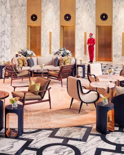 a lobby with tables and chairs and a man in a suit at Royal Mansour Casablanca in Casablanca