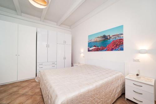 a white bedroom with a bed and a painting on the wall at Villa Geraldina con piscina in Torre Suda