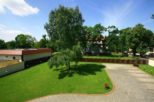 a green yard with a tree and a building at PAŁACYK BUDGET in Legnica