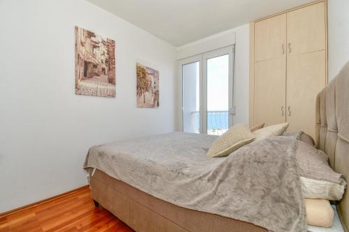 a bedroom with a bed and a large window at Trstenik Beach Apartment in Split