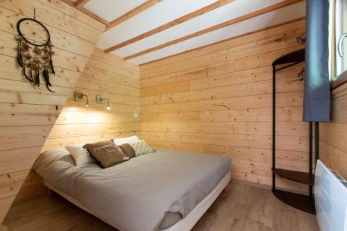 une chambre avec un lit dans un mur en bois dans l'établissement Lodge du Berlandou, à Escragnolles