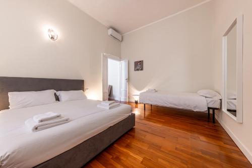 - une chambre avec 2 lits, des murs blancs et du parquet dans l'établissement Cortivo House - Silva 45 next to metro Lotto, à Milan