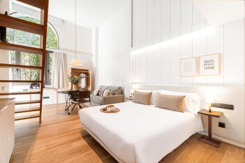 a white bedroom with a large bed and a chair at Casa Bella Gracia by Aspasios in Barcelona