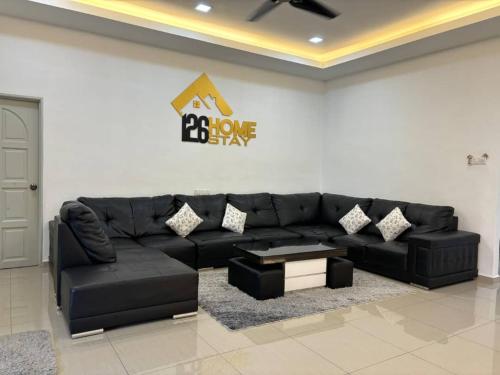 a living room with a black leather couch and a sign at 126 Homestay TYPE B in Tangkak
