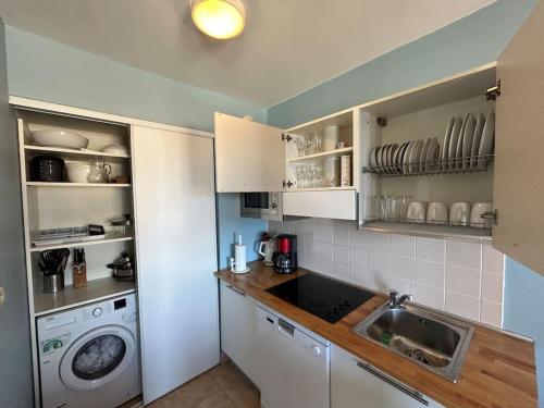 une cuisine avec un évier et une machine à laver dans l'établissement Sunnydaze Monaco beach apartment, à Beausoleil