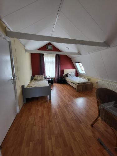 an attic room with two beds and a wooden floor at vakantie appartement Stadskanaal in Stadskanaal