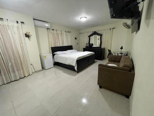 1 dormitorio con cama, sofá y TV en Maria's Entire House HIGUEY 2BD, en Higüey