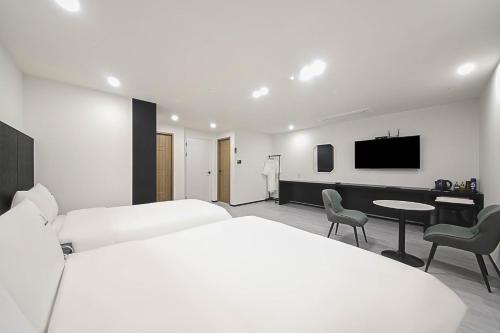 a bedroom with a white bed and a table and chairs at Busan Seomyeon Broa Hotel in Busan