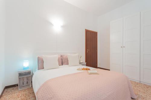 a white bedroom with a large bed with a plate of fruit on it at Nonna Tere Apartment by Rent All Como in Carate Urio