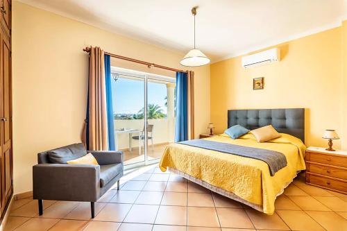 een slaapkamer met een bed, een stoel en een raam bij VILLA EBER - independent 1 & 2 bedroom apartments, pool, air con, fast Wi-Fi, near old town of Albufeira and beaches in Albufeira