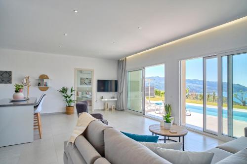 een woonkamer met een bank en een zwembad bij Lefkimmiatis Villas Corfu in Afionas