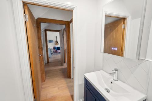 a bathroom with a sink and a mirror and a hallway at Beautiful 1 bedroom apartment with free on street parking in Oban
