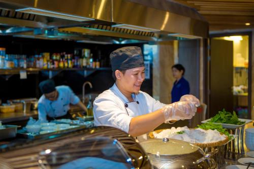 a chef preparing food in a restaurant kitchen at Alana Nha Trang Beach Hotel in Nha Trang