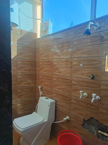 baño con aseo y pared de madera en Babu seva, en Govardhan