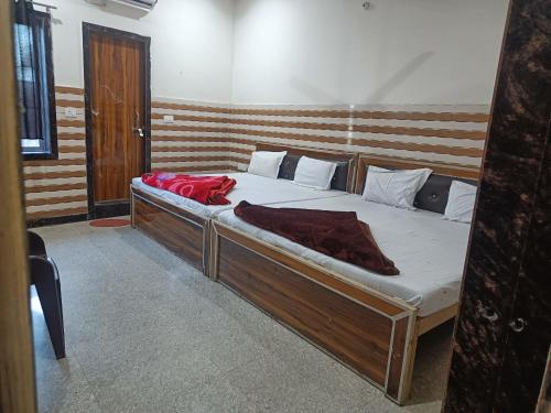 uma cama de madeira com um cobertor vermelho em Babu seva em Govardhan