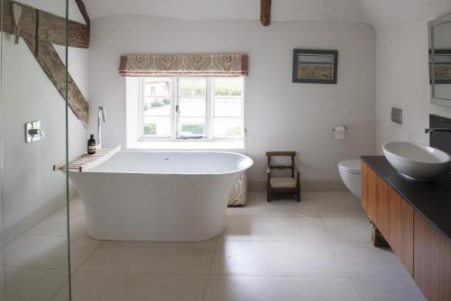 a bathroom with a large tub and a sink at Fabulous Farmhouse in Hampshire in London