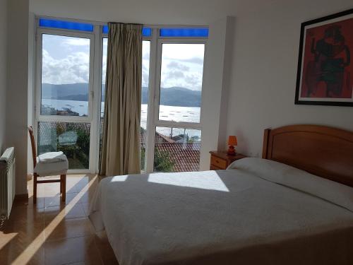 a bedroom with a bed and a large window at APARTAMENTOS CANADA 2 in Raxó