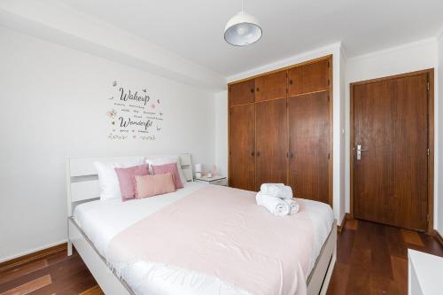 una camera da letto con un grande letto bianco con cuscini rosa di GuestReady - A brilliant stay near Alma Mall a Coimbra
