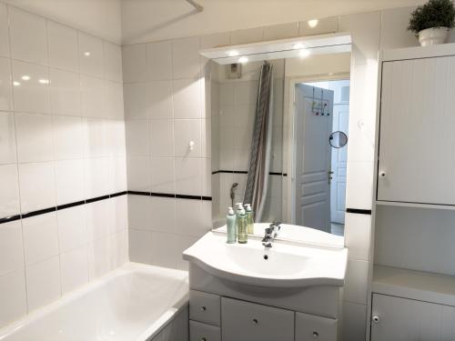 a white bathroom with a sink and a bath tub at Les Galets - Duplex avec jardin - 2 chambres et bureau in Pau