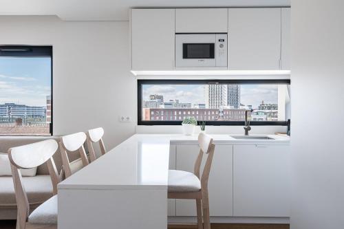 a white kitchen with a table and chairs and a window at GuestReady - A Slice of Aveiro in Aveiro
