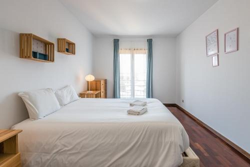 ein Schlafzimmer mit einem großen weißen Bett mit Handtüchern darauf in der Unterkunft GuestReady - Espinho Beach Flat in Espinho