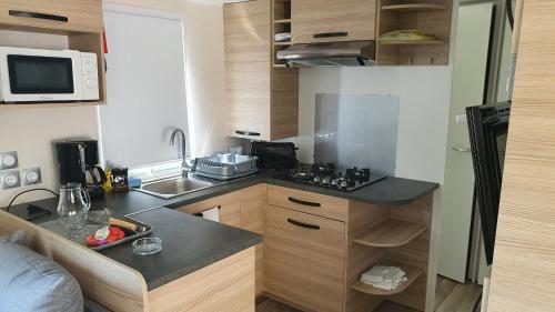une petite cuisine avec un évier et un micro-ondes dans l'établissement Superbe Mobil home 3 chambres F51, à Saint-Jean-de-Monts