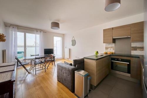 une cuisine et un salon avec un canapé et une table dans l'établissement Cosy appartement direct PARIS La Défense, à Rueil-Malmaison