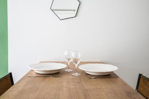 - une table avec 2 assiettes blanches et des verres à vin dans l'établissement Central Part-Dieu - Appartement 1, à Lyon