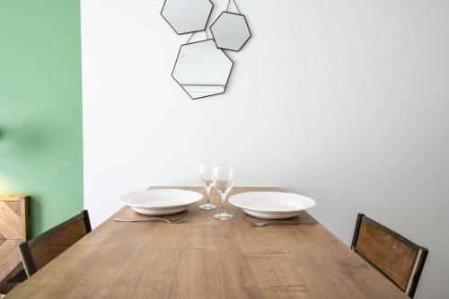 - une table à manger avec 2 assiettes blanches et des verres à vin dans l'établissement Central Part-Dieu - Appartement 1, à Lyon