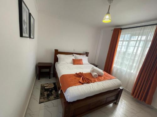 a bedroom with a bed with an orange blanket at Ankar Homes, California 2 in Nanyuki