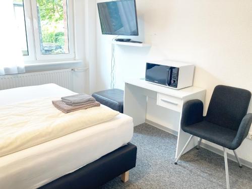 a bedroom with a bed and a tv and a chair at Haus Hanseatic in Helgoland