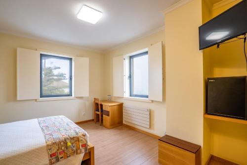 a bedroom with a bed and a flat screen tv at B&B Pensão Avenida in Oliveira de Frades
