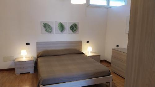 a bedroom with a bed and two night stands and two lamps at Appartamenti La Rosa dei Venti in Lacona