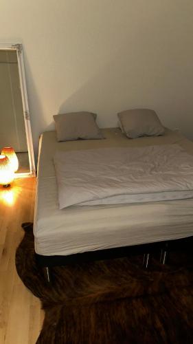 uma cama com lençóis brancos e almofadas num quarto em Cost central flat em Aalborg
